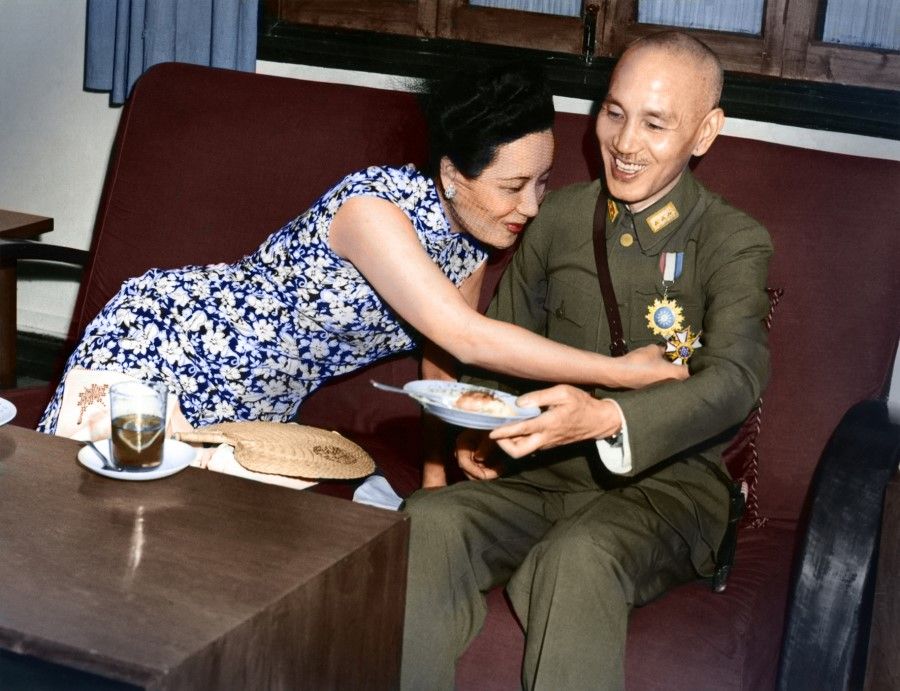 7 July, 1943, Chungking - Madame Chiang Kai-shek, wearing a veil, is leaning over to touch the medal just pinned on Gen. Chiang Kai-shek's uniform by Lt. Gen. Joseph Stilwell, the US Commander of the CBI Theater. The Legion of Merit medal was presented on behalf of US President Roosevelt to Chiang, who served as the supreme Allied commander in China and acting president. Madame Chiang is showing a proud smile and Chiang, caught off guard, is trying to balance the cake plate in his hand. The photographer catches a spontaneous moment between the top Chinese leader and the first lady.