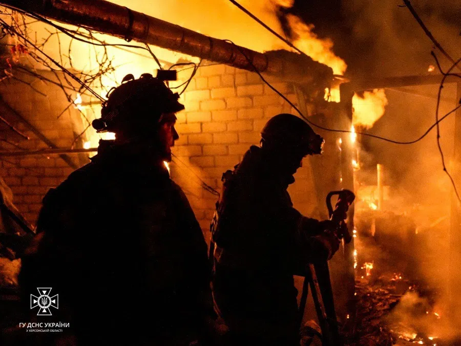 This handout photograph taken and released by Ukrainian State Emergency Service on 24 November 2023 shows rescuers putting out a fire in a house, following a Russian shelling in Kherson. (Handout/Ukrainian State Emergency Service/AFP)
