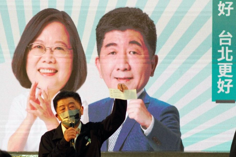 Chen Shih-chung, Taipei's mayoral candidate from the ruling Democratic Progressive Party (DPP), holds up a cheque in front of an image of him along with Taiwanese President Tsai Ing-wen during an election campaign rally in Taipei on 5 November 2022. (Sam Yeh/AFP)