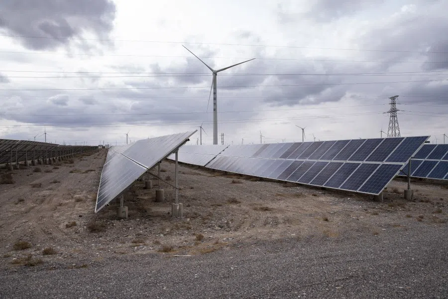 Solar panels and a wind turbine on the outskirts of the new city area of Yumen, Gansu province, China on 31 March 2021. (Qilai Shen/Bloomberg)