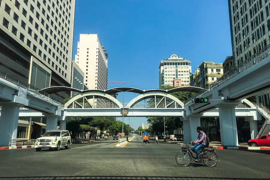 A man on a bicycle rides through a near-empty street intersection in Yangon, Myanmar on 1 February 2022. (AFP)