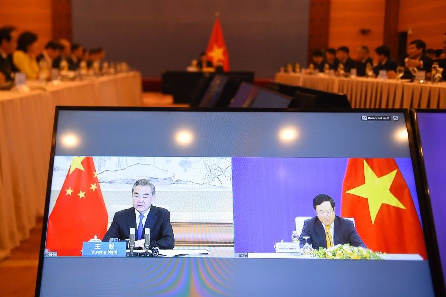 The online meeting between Vietnam's Foreign Minister Pham Binh Minh (R) with his Chinese counterpart Wang Yi (L) is pictured on a monitor during the 12th "Meeting of the China-Vietnam Steering Committee for Bilateral Cooperation", being held virtually due to restrictions over the COVID-19 coronavirus, in Hanoi on 21 July 2020. The two countries held the virtual meeting as they seek to mediate a dispute over the South China Sea. (Photo by Nhac NGUYEN / AFP)
