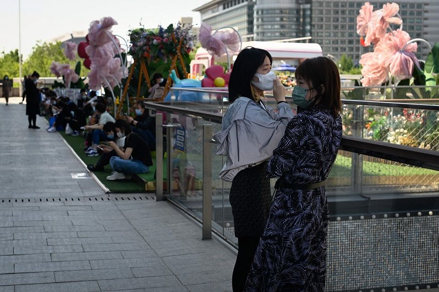 Two women chat outside a mall in a business district in Beijing, China, on 16 May 2022. (Wang Zhao/AFP)