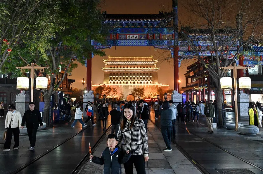 People take pictures of the Zhengyangmen Archery tower as they visit the Qianmen street in Beijing on 15 November 2024. (Adek Berry/AFP)