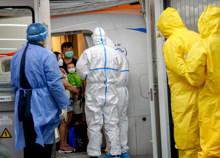 Workers in protective suits await passengers from a Xiamen Airlines airplane as they get off at Wuhan Tianhe International Airport in Wuhan, Hubei province, 31 January 2020. There was initial uncertainty over human-to-human transmission of the Wuhan coronavirus. (Reuters)