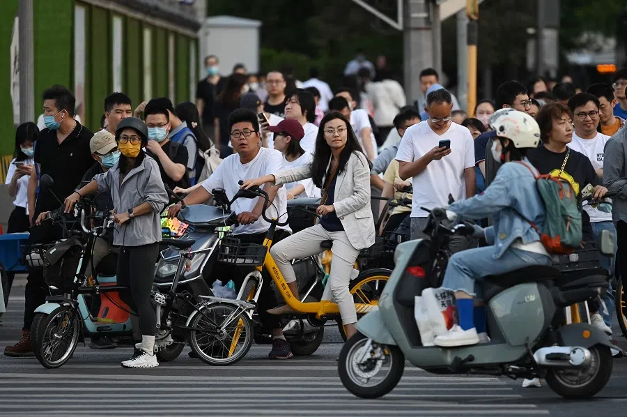People wait to cross a road at rush hour in Beijing, China, on 22 May 2023. (Greg Baker/AFP)