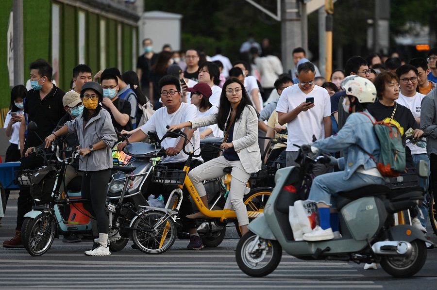People wait to cross a road during rush hour in Beijing, China, on 22 May 2023. (Greg Baker/AFP)