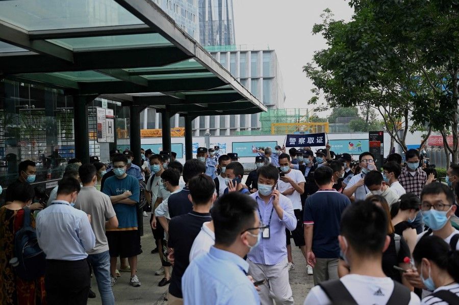 People gather at the Evergrande headquarters building in Shenzhen, southeastern China on 15 September 2021, as the Chinese property giant said it is facing "unprecedented difficulties" but denied rumours that it is about to go under. (Noel Celis/AFP)