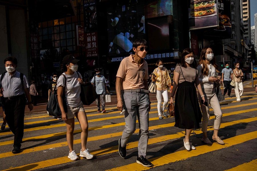 People cross a street in a shopping district in Hong Kong on 5 September 2022. (Isaac Lawrence/AFP)