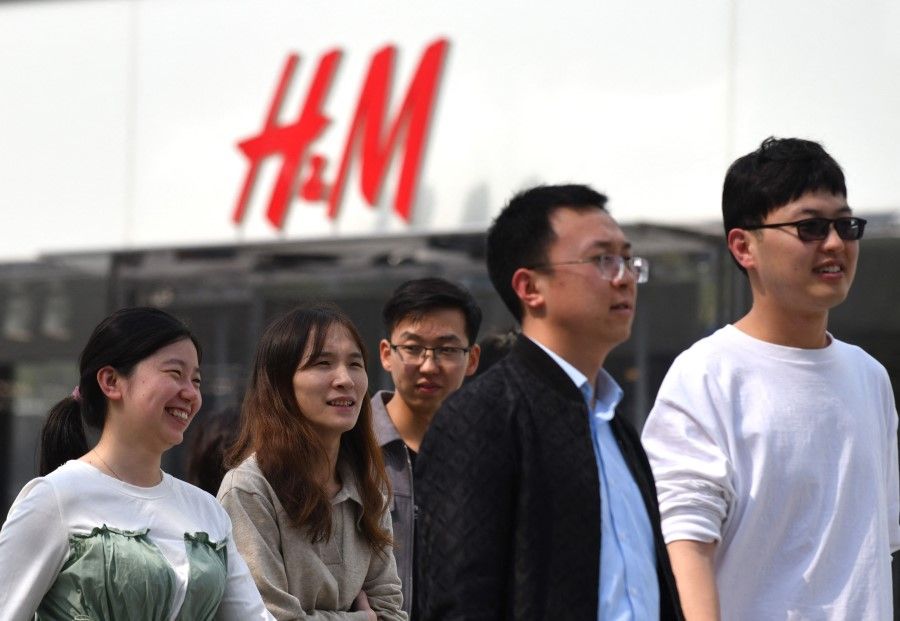 People walk past an H&M clothing store in Beijing on 25 March 2021. (Greg Baker/AFP)