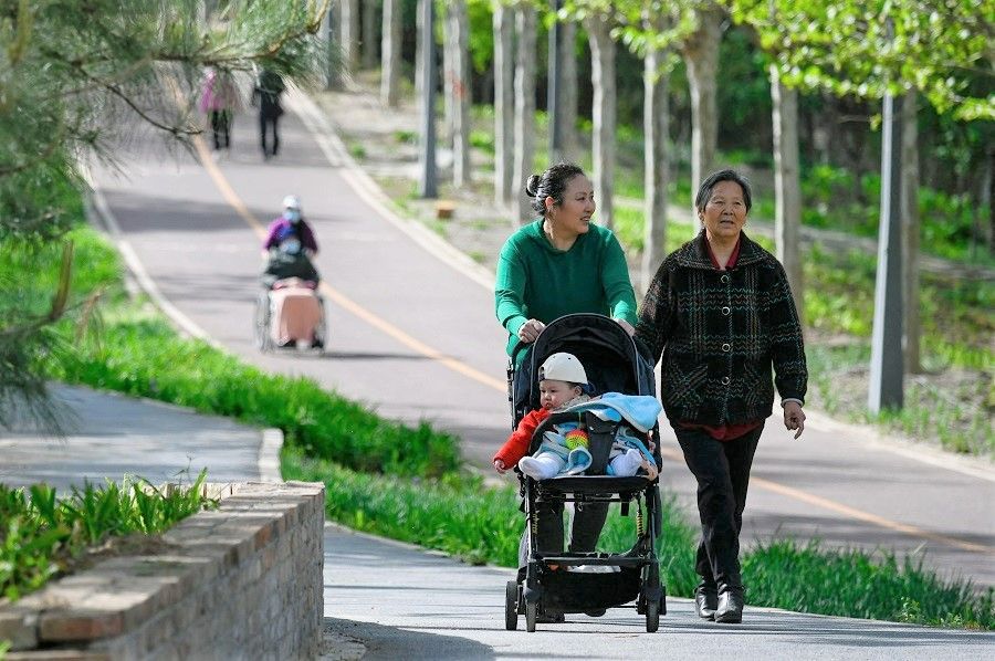 People walk in a public park in Beijing, China, on 15 April 2023. (Wang Zhao/AFP)