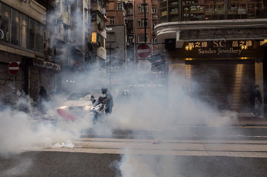 A motorist is enveloped in smoke after riot police deployed tear gas to clear protesters from a road during a rally against a new national security law in Hong Kong on 1 July 2020. (Dale De La Rey/AFP)