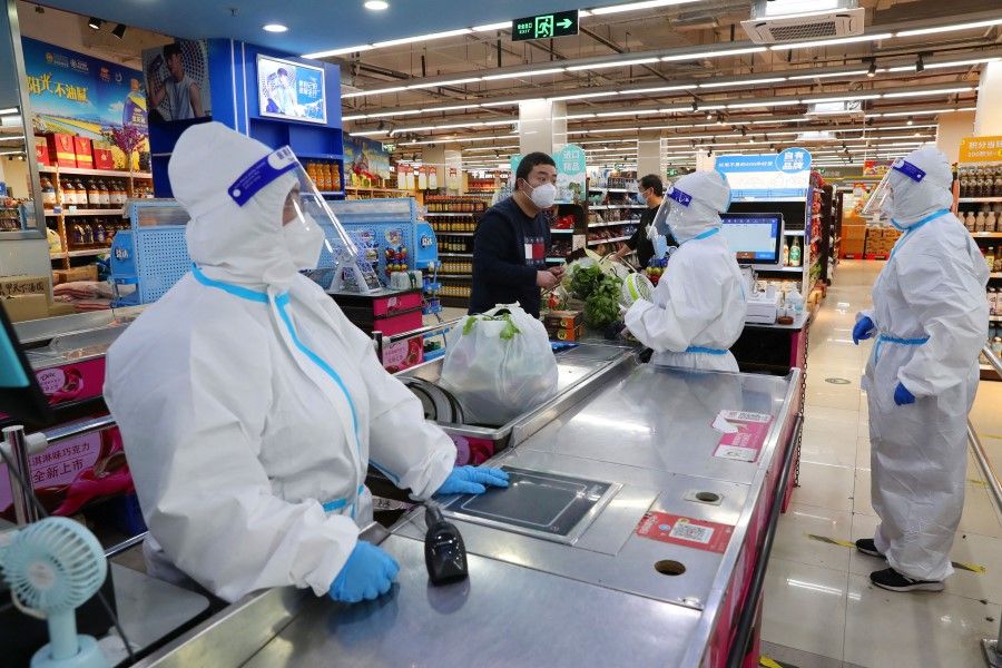 Workers in protective suits attend to a customer at a checkout counter of a reopened supermarket, amid the Covid-19 outbreak, in Shanghai, China, 5 May 2022. (China Daily via Reuters)