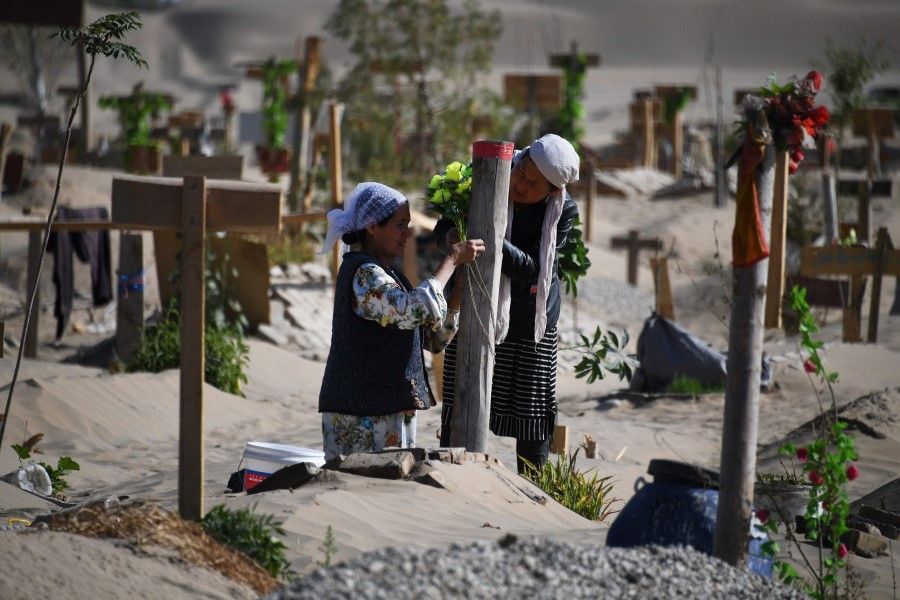 This file photo taken on 31 May 2019 shows two women decorating a grave in a Uighur graveyard on the outskirts of Hotan in China's northwest Xinjiang region. The US Congress was set 27 May 2020 to authorise sanctions against Chinese officials over the mass incarceration of Uighur Muslims. (Greg Baker/AFP)