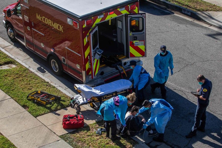 County of Los Angeles paramedics administer oxygen to a potential Covid-19 patient on the sidewalk before taking him to a hospital in Hawthorne, California on 29 December 2020. (Apu Gomes/AFP)