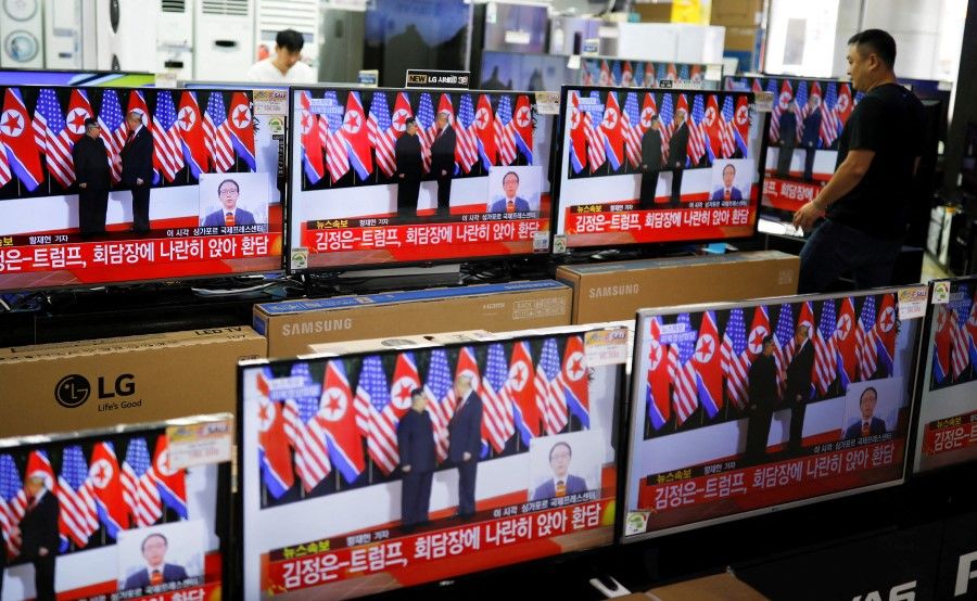 A shopkeeper walks past a set of TVs broadcasting a news report on a summit between the US and North Korea, in Seoul, South Korea, 12 June 2018. (Kim Hong-Ji/Reuters)