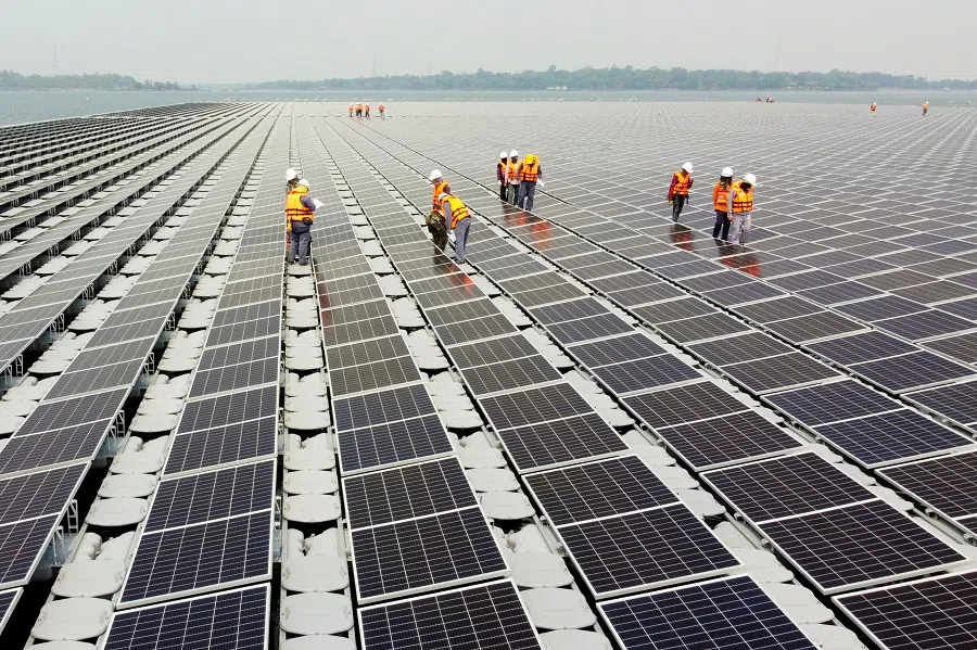 A drone photo of workers walking between solar cell panels over the water surface of Sirindhorn Dam in Ubon Ratchathani, Thailand, on 8 April 2021. (Prapan Chankaew/Reuters)