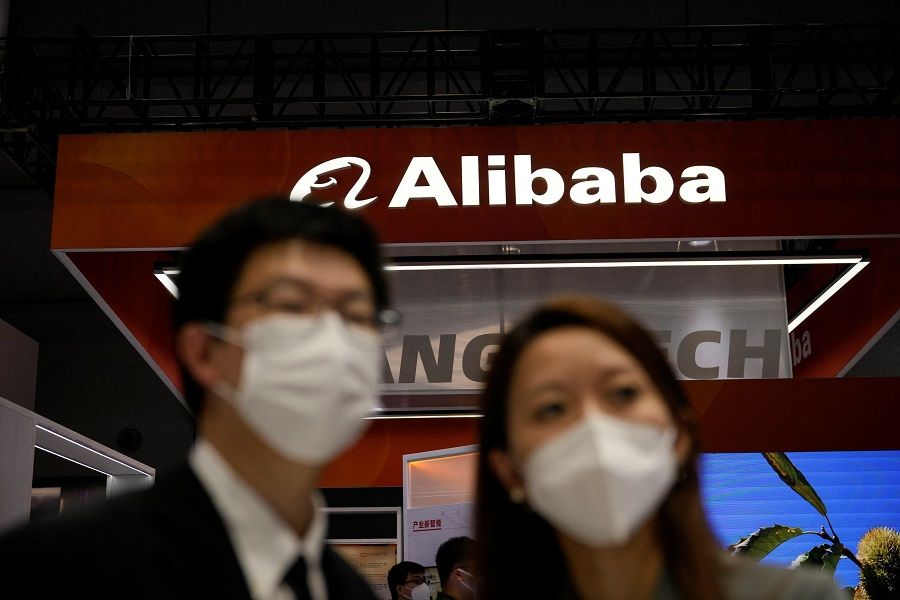 People stand in front of a sign of Alibaba Group during the World Artificial Intelligence Conference, in Shanghai, China, 1 September 2022. (Aly Song/Reuters)
