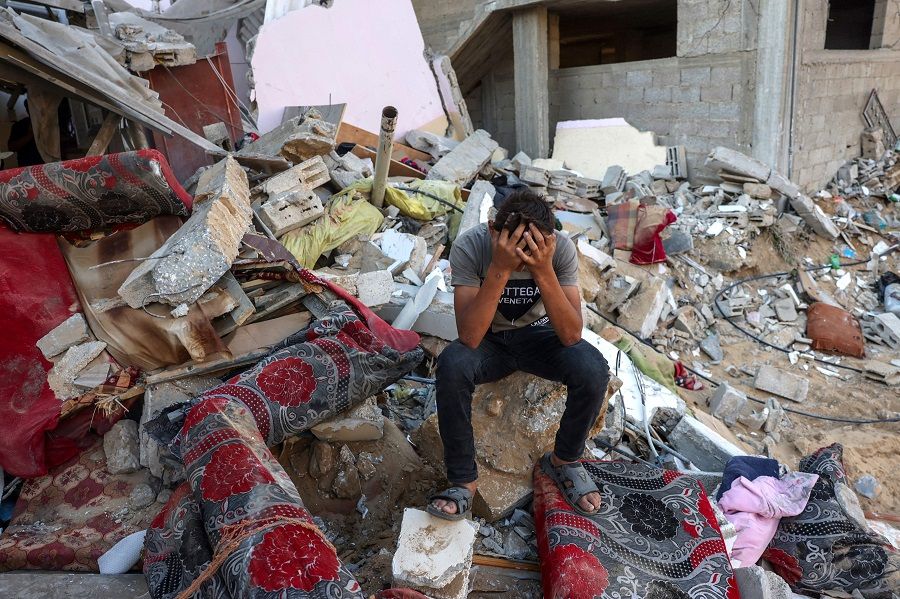 A Palestinian youth reacts as he sits on the rubble of a destroyed home following an Israeli military strike on the Rafah refugee camp, in the southern Gaza Strip on 15 October 2023, amid the ongoing battles between Israel and Hamas. (Mohammed Abed/AFP)