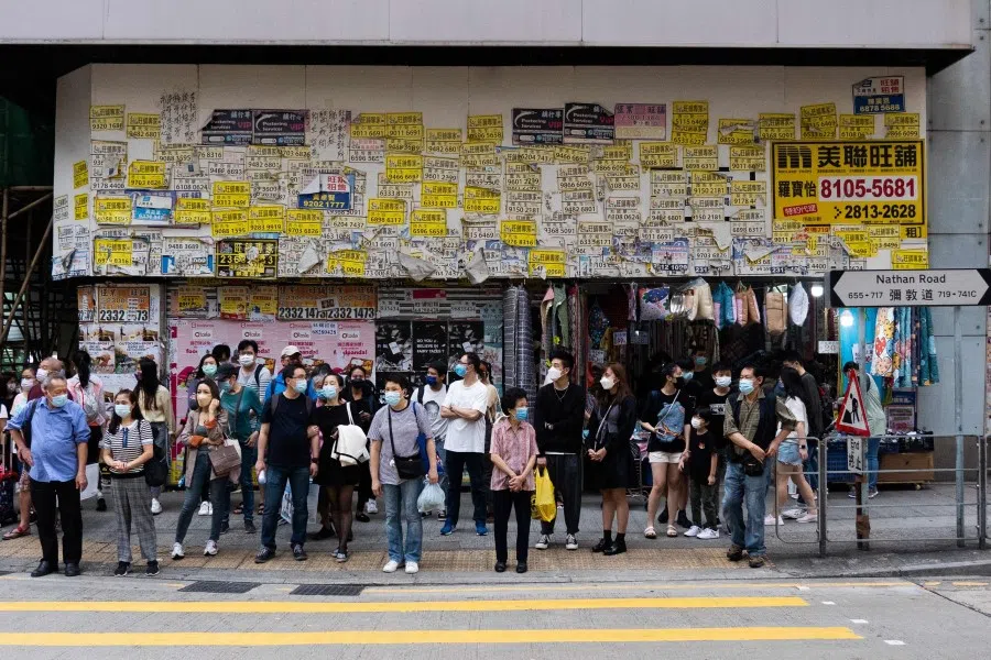 Pedestrians wait to cross a street in Hong Kong on 31 October 2021. (Bertha Wang/AFP)