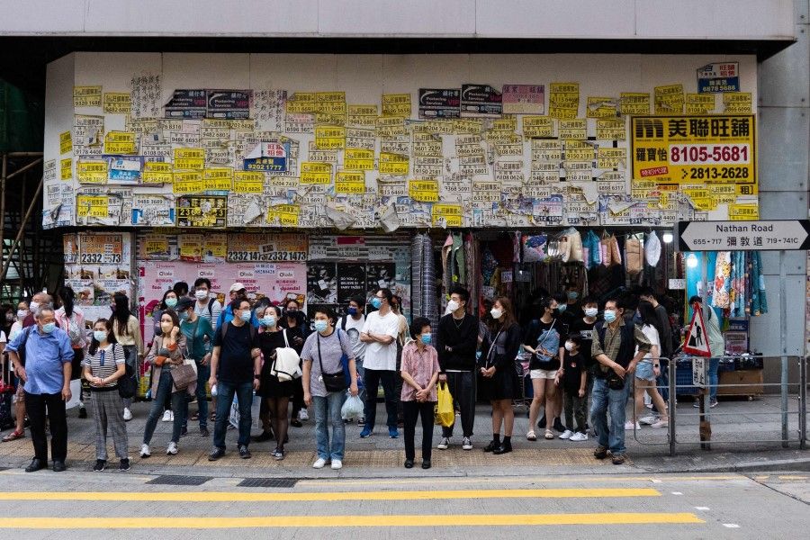 Pedestrians wait to cross a street in Hong Kong on 31 October 2021. (Bertha Wang/AFP)