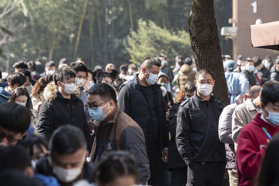 People wearing protective masks stand in line at a Covid-19 testing center in Shanghai, China, on 6 February 2021. (Qilai Shen/Bloomberg)