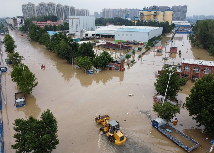An aerial view shows rescue workers evacuating residents on a flooded road following heavy rainfall in Zhengzhou, Henan province, China, 22 July 2021. (Aly Song/Reuters)