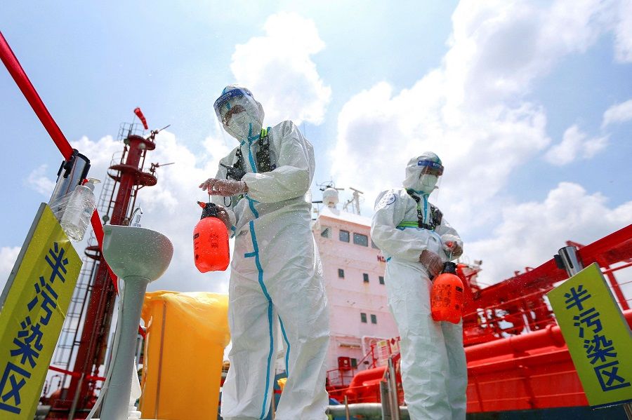 This file photo taken on 4 August 2021 shows police officers wearing protective gear against the spread of Covid-19 spraying disinfectant at Nanjing port, Jiangsu province, China. (AFP)