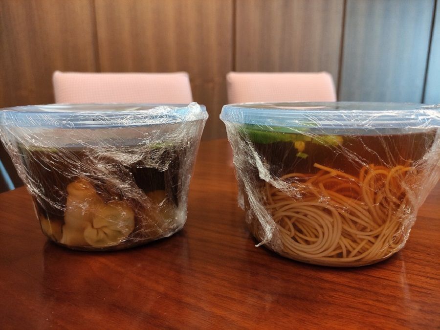 Noodle soup packed in a plastic container and wrapped in cling film to prevent spillage during delivery.