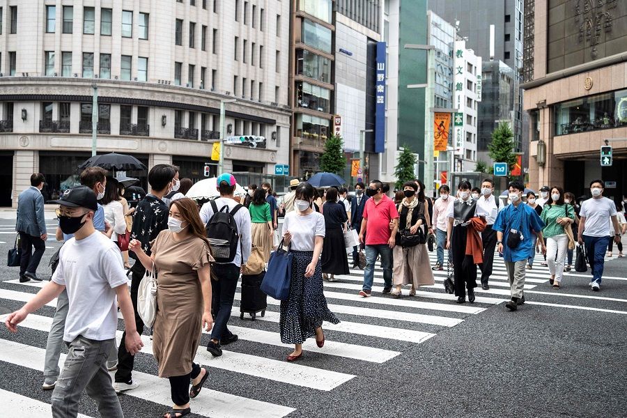 People cross a street in Tokyo's Ginza area in Japan on 22 June 2021. (Charly Triballeau/AFP)