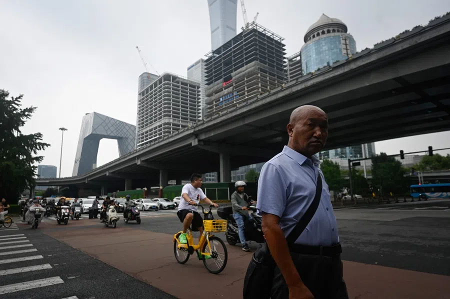 People cross a street in Beijing, China, on 15 July 2025. (Wang Zhao/AFP)