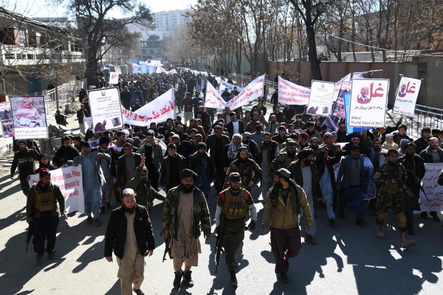 People hold placards as they march during a protest against the recent remarks by U.S. President Joe Biden to freeze Afghanistan's assets, in Kabul on 15 February 2022. (Sahel Arman/AFP)