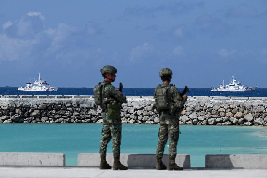 Philippine soldiers look at Philippine Coast Guard vessels near Thitu Island in the disputed South China Sea on 1 December 2023. (Jam Sta Rosa/AFP)