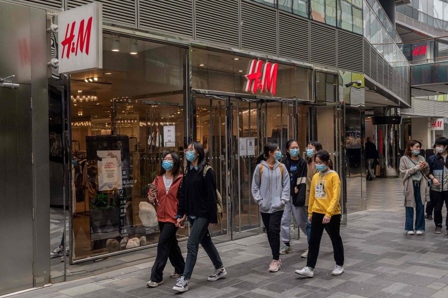 People walk past an H&M store in Beijing on 5 April 2021. (Nicolas Asfouri/AFP)