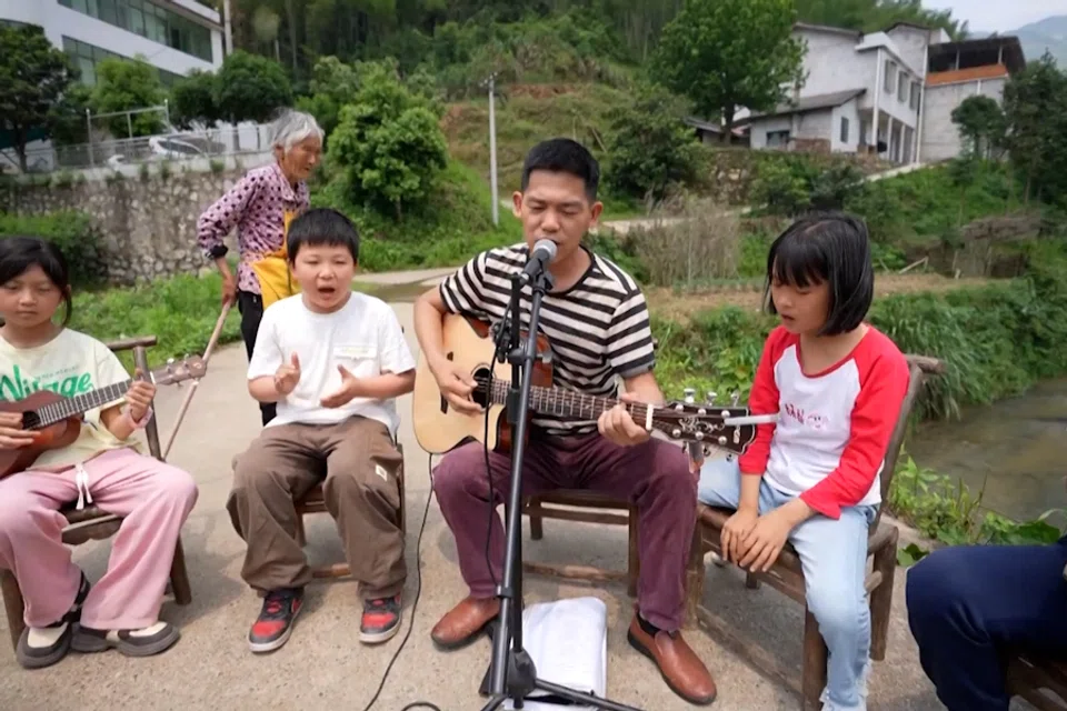 Volunteer teacher Wen sings with the Miaoxi Primary School band in Hengyang county, Hunan. (Screen grab from CCTV)