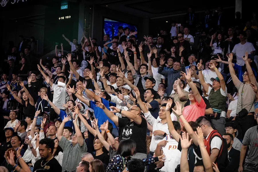 People on the stands wave during the NBA pre-season basketball game between the Phoenix Suns and the Brooklyn Nets at the Venetian Arena in Macau on 12 October 2025. (Eduardo Leal/AFP)