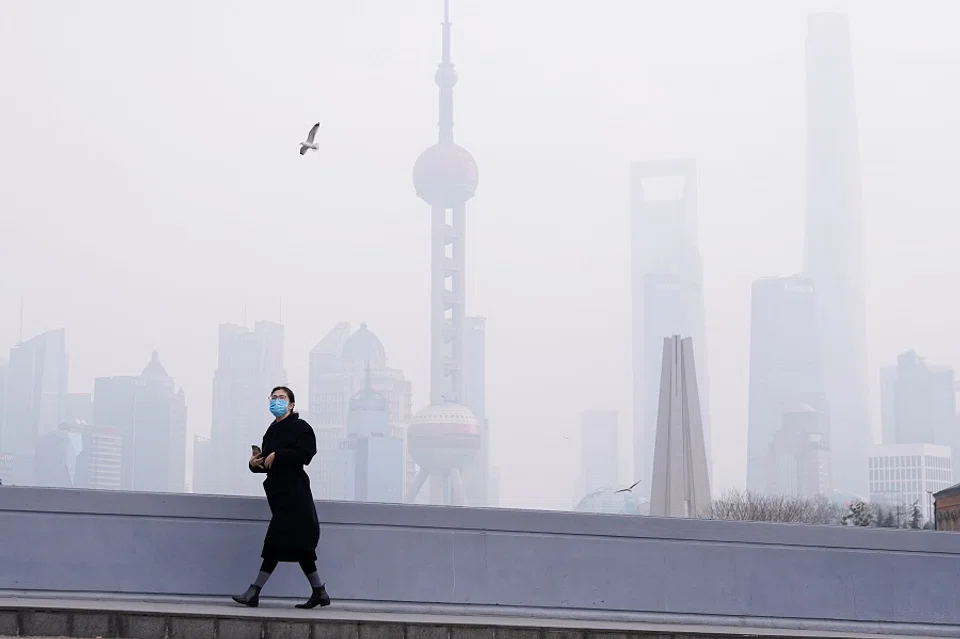 In this photo taken on 3 February 2020, a woman wearing a mask is seen on a bridge in front of the financial district of Pudong, Shanghai, China, as the country is hit by the Covid-19 pandemic. (Aly Song/Reuters)