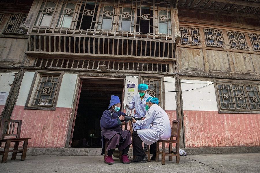 A resident (left) receives a Covid-19 vaccine in Danzhai county, Qiandongnan Miao and Dong Autonomous Prefecture, in Guizhou province, China, on 12 December 2022, as medical workers vaccinate people who can't go out conveniently from their homes. (AFP)