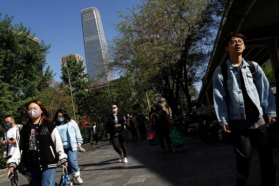 People walk on a street during morning rush hour, in Beijing, China, 18 April 2023. (Tingshu Wang/Reuters)