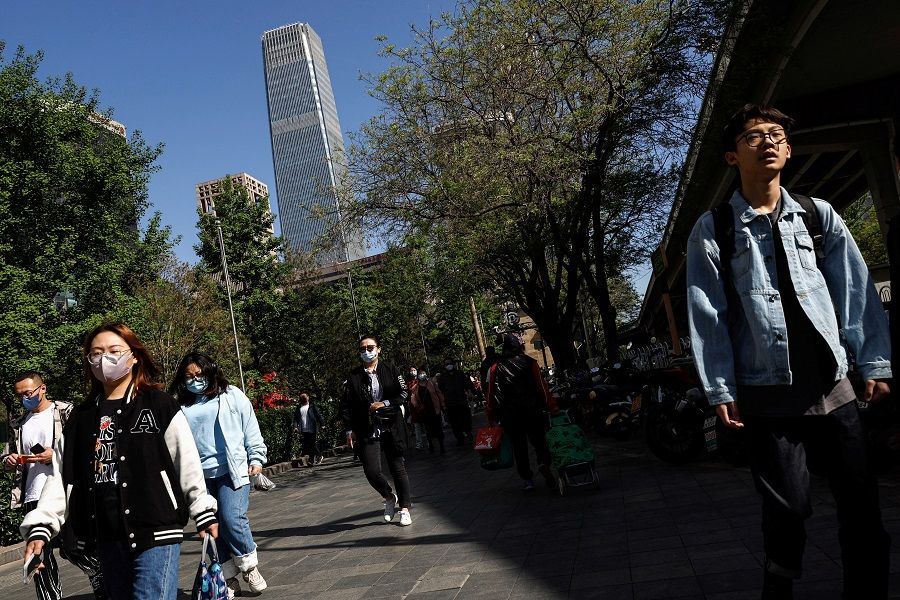 People walk on a street during morning rush hour, in Beijing, China, 18 April 2023. (Tingshu Wang/Reuters)
