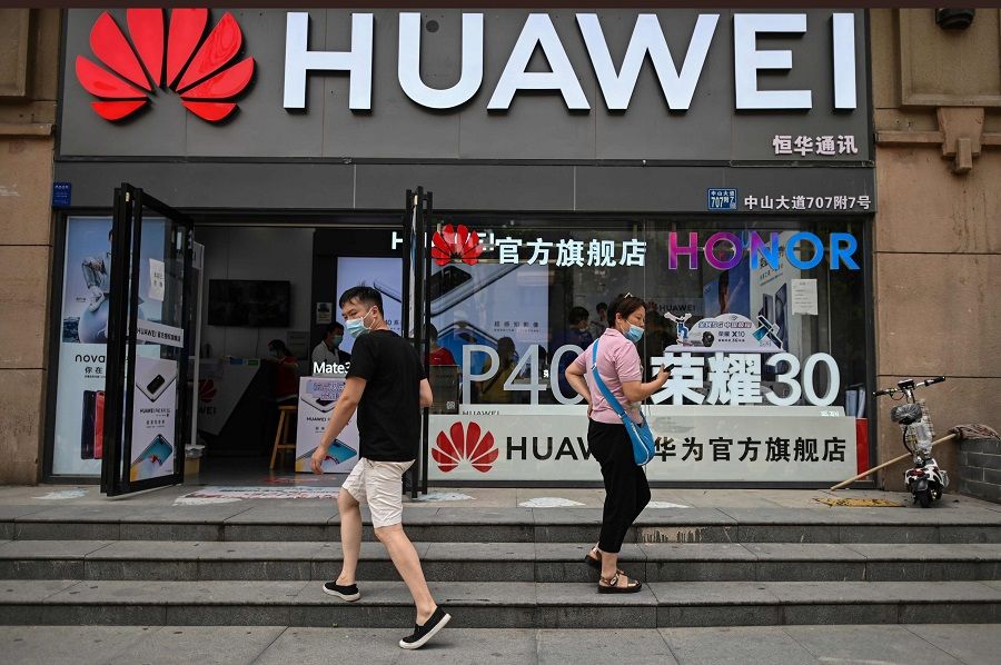 People wearing face masks walk outside a Huawei store in Wuhan, Hubei, China, on 26 May 2020. (Hector Retamal/AFP)