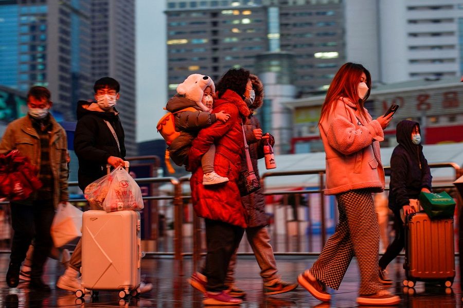 People wearing protective masks walk at the Shanghai Railway Station, in Shanghai, China, 27 January 2022. (Aly Song/Reuters)