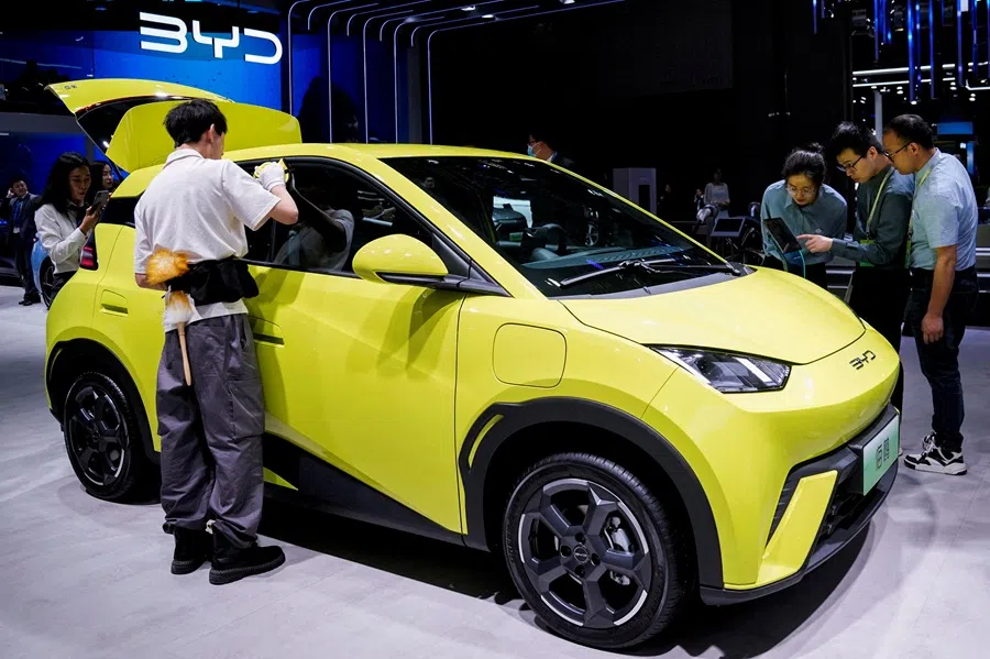 People use their phones in front of the BYD Seagull that is displayed at the Auto Shanghai show, in Shanghai, China, on 19 April 2023.