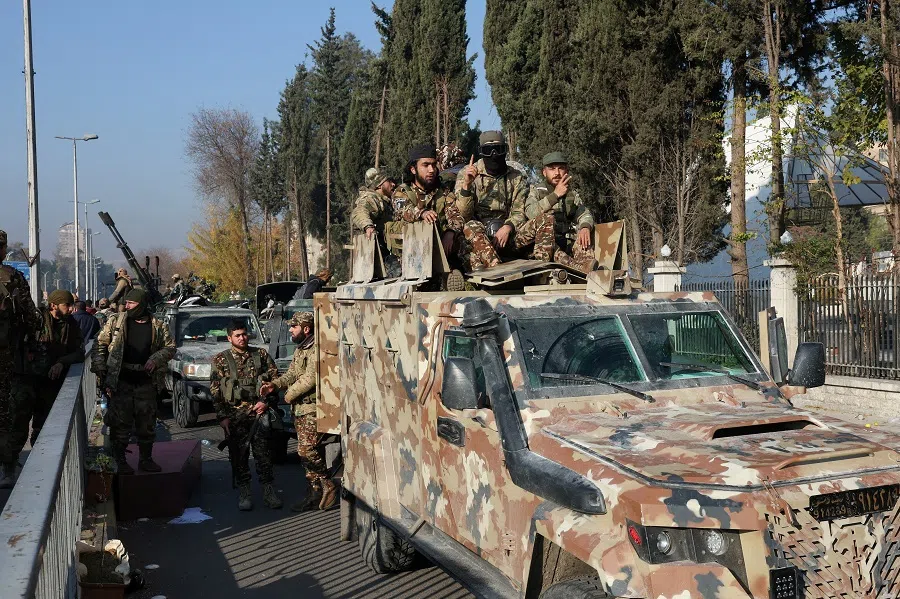 Rebel fighters sit on a vehicle, after rebels seized the capital and ousted President Bashar al-Assad, in Damascus, Syria, on 9 December 2024.