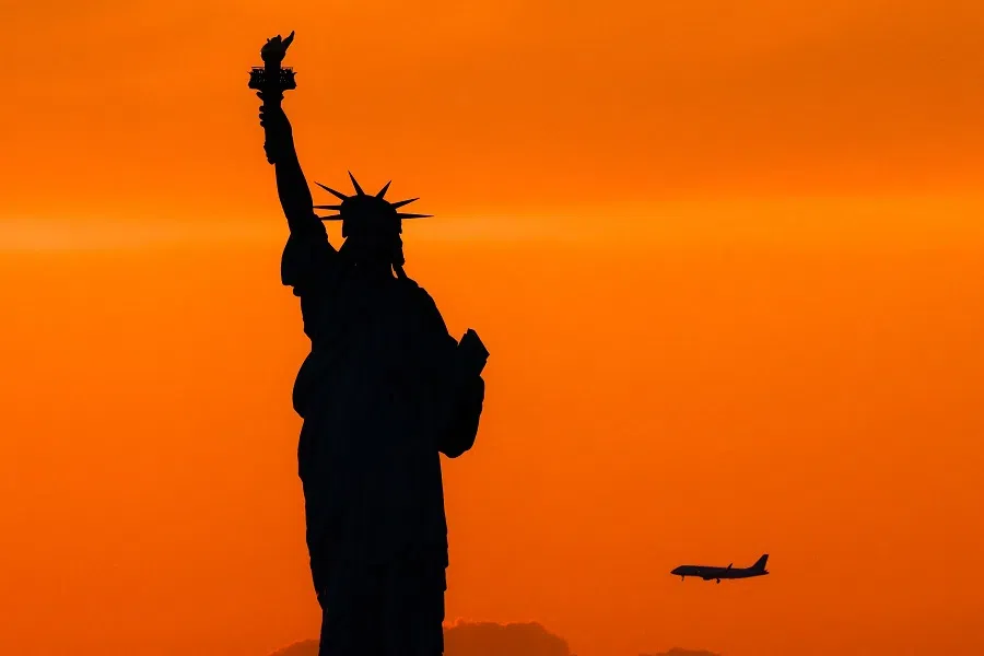 The Statue of Liberty is seen at dusk while a passenger aircraft approaches Newark airport in New York, US on 11 August 2024.