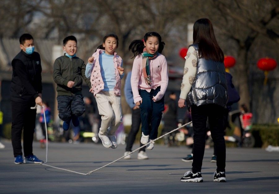 Children play a jump rope game in a park in Beijing on 9 February 2021. (Noel Celis/AFP)