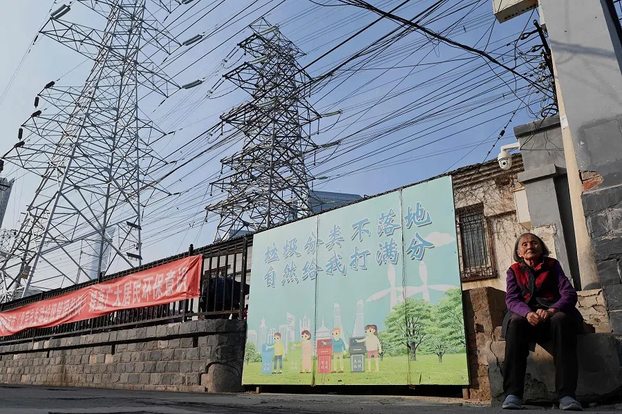 A woman sits below power lines in Beijing, China, on 13 October 2021. (Noel Celis/AFP)