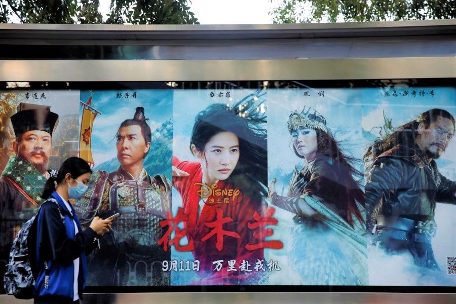 A woman walks past an advertisement promoting Disney's movie Mulan at a bus stop in Beijing, 9 September 2020. (Carlos Garcia Rawlins/Reuters)
