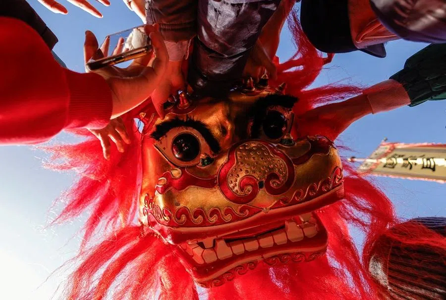 Visitors touch a head of a traditional lion costume during celebrations on the first day of the Lunar New Year at the Dongyue Temple in Beijing, China, on 17 February 2026.