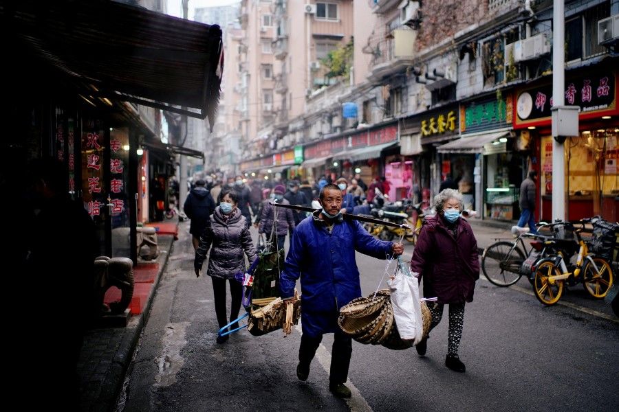 People wearing protective masks walk at a street market almost a year after the start of the coronavirus disease (COVID-19) outbreak, in Wuhan, Hubei province, China, 7 December 2020. (Aly Song/REUTERS)